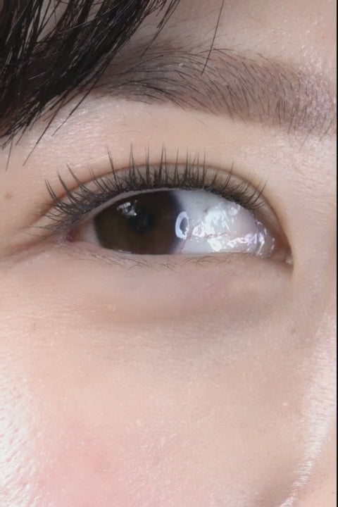 Woman with monolid eyes applying at-home DIY eyelash extensions